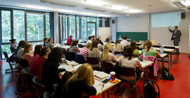 Blick in ein Uniseminar mit einer Grupppe von Studierenden und einem Dozenten an der Tafel