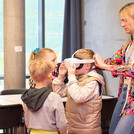 Erwachsener setz einem Kind eine VR-Brille auf