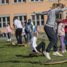 Ein Mädchen springt auf einem runden Spielgerät in die Luft. Weitere Kinder spielen im Hintergrund.