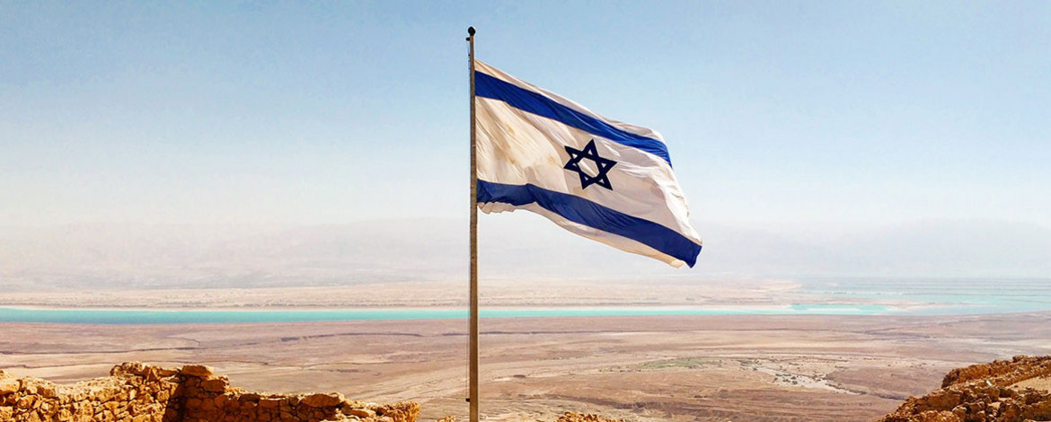 Israelische Flagge im Vordergrund, im Hintergrund Landschaft - 