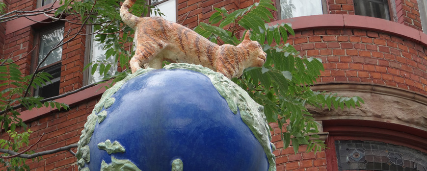Skulptur von Katze auf Globus vor Gebäude auf Campus