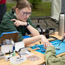 Ein Kind mit einem Lötkolben und eine erwachsene Person erklärt.