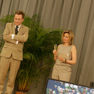 Moderatorin Kristina Tschesch und Präsident Günther stehen auf der Bühne und betrachten einen Bildschirm.