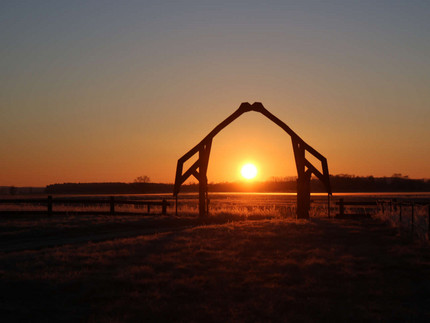 Sonnenaufgang unterhalb einem Tor, das aussieht wie zwei Kraniche