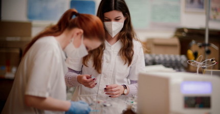 Foto von zwei Wissenschaftlerinnen, die ein Laborexperiment durchführen.