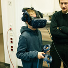 Kind mit VR Brille im Hintergrund ein Erwachsener