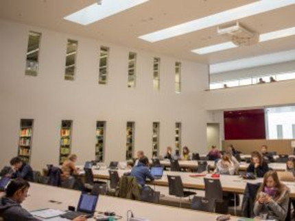 Studierende sitzen an den Arbeitsplätzen in einem großen Lesesaal der Universitätsbibliothek