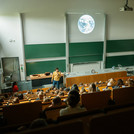 Blick auf einen Hörsaal mit grüner Tafel und der Projektion der Erde an der Leinwand