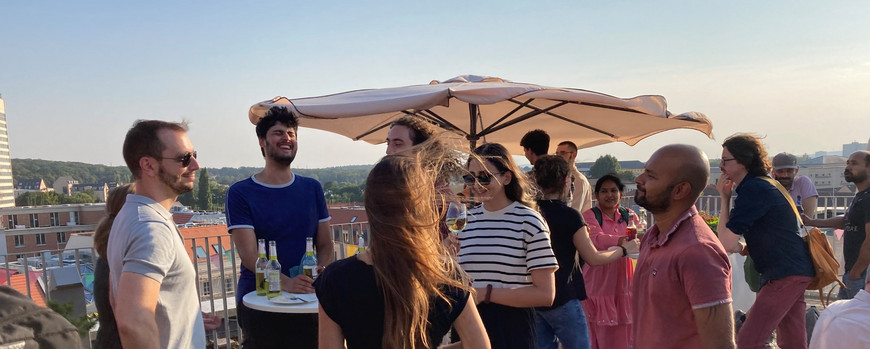 Menschen stehen beisammen auf deiner Dachterrasse und reden miteinander.