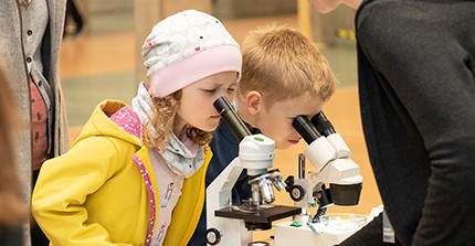Zwei Kinder schauen durch ein Mikroskop