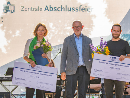 3 Personen mit 2 großen symbolischen Schecks