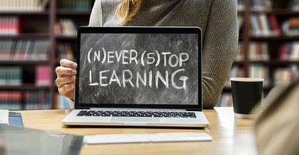 Ein Laptop aufgeklappt, auf dem Bildschirm steht: (N) EVER (S) TOP LEARNING