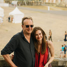 Ein*e Absolvent*in posiert mit Gast auf den Treppenstufen von Haus 9 am Neuen Palais.