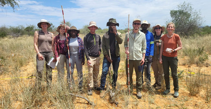 Group picture of NamTip researchers holding measuring devices in their hands and with savanna rangeland in the background