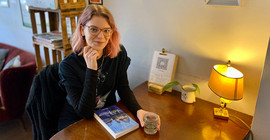 Potsdamer Lehramtsstudentin Sophie-Marie Gruber sitzt an einem Tisch, vor ihr liegt ihr Buch „Großstadtgeheimnisse“.