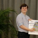 Absolventenpreisübergabe zwischen zwei Personen. Bei halten einen großen Check vor sich in die Kamera. Eine der Personen präsentiert außerdem ein Buch.