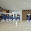 Roll-Ups aufgereiht im Foyer der Bibliothek Golm. Auf den Roll-Ups sind einzelne Personen abgebildet die ihre Geschichte erzählen. Auf den Roll-Ups sind QR-Codes zu den Podcasts mit diesen Personen.