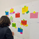 Participant of the DH Jewish Hackathon 2022 reads colorful Post-Its on the wall.