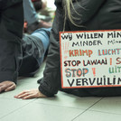 An activist sits on the floor with a sign describing the impact of aviation