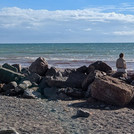 Studierende sitzen am Strand und blicken aufs Meer