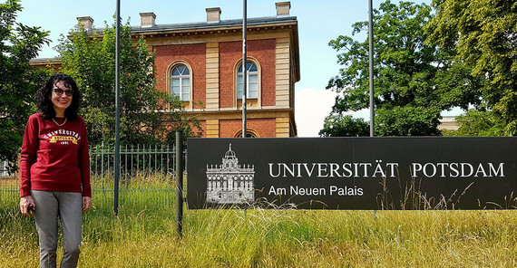 Prof. Dr. Cornelia Klettke steht neben dem Schild der Universität Potsdam, Campus am Neuen Palais