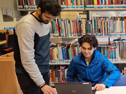 Arbeitssituation des Praktikanten mit einem Kollegen am Laptop