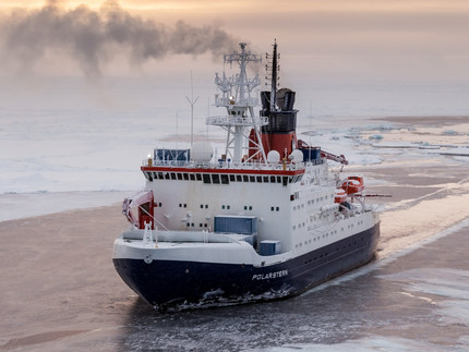 Das Forschungsschiff "Polarstern", ein weiß-blaues Schiff, fährt durch ein mit Seeeis überdecktes Meer.