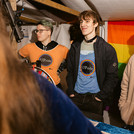 Drei Personen mit bunten T-Shirts an einem Marktstand