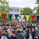 Viele Kinder auf einem Platz zwischen Bäumen und Gebäuden