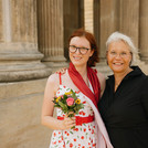 Absolvent*in posiert mit Familienmitglied lachend vor der Kamera.