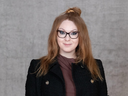 Frau mit rotblonden Haaren und Brille.