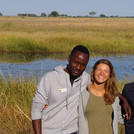 a group of people standing a front of a river between grassland