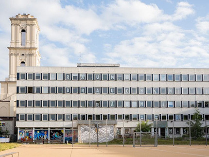 Im Vordergrund ein Plattenbau, im Hintergrund ein Kirchturm ohne Kuppel