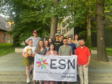 Mehrere Personen stehen auf einer Treppe mit einer Flagge mit ESN Logo