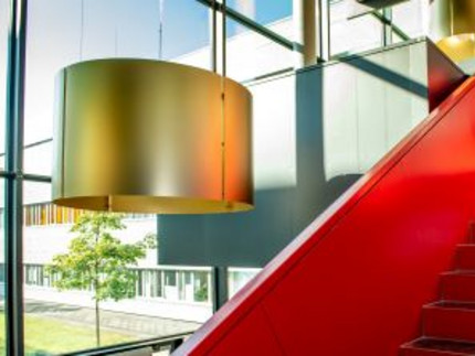 Rote Treppe in einem Foyer mit großem Glasfenster und Blick in den Innenhof