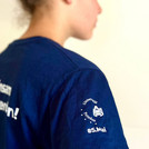 T-Shirt Ärmel im Fokus. Darauf zu sehen das Universitäts Logo und der #5.Mai.