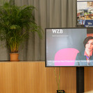 Jutta Allmendinger, Ph.D., Präsidentin des Wissenschaftszentrums Berlin für Sozialforschung gGmbH, in einer Videobotschaft auf einem Bildschirm vor der Bühne.