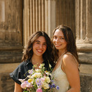 Zwei Absolvent*innen vor den Säulen der Kolonnade.