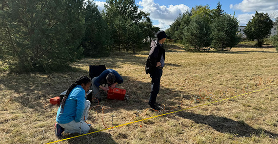 Die Studierenden Mercy Ekua Grimmon-Thompson (links) und Diyorbek Toshniyozov (r.) schließen gemeinsam mit Jens Tronicke die Kabel für die Geoelektrik-Messungen an.