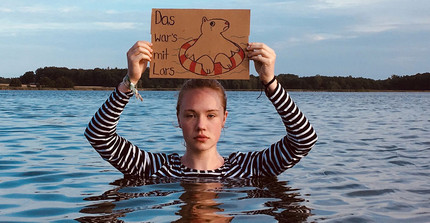 Lena Gundelfinger steht in der Ostsee und hält ein Schild.