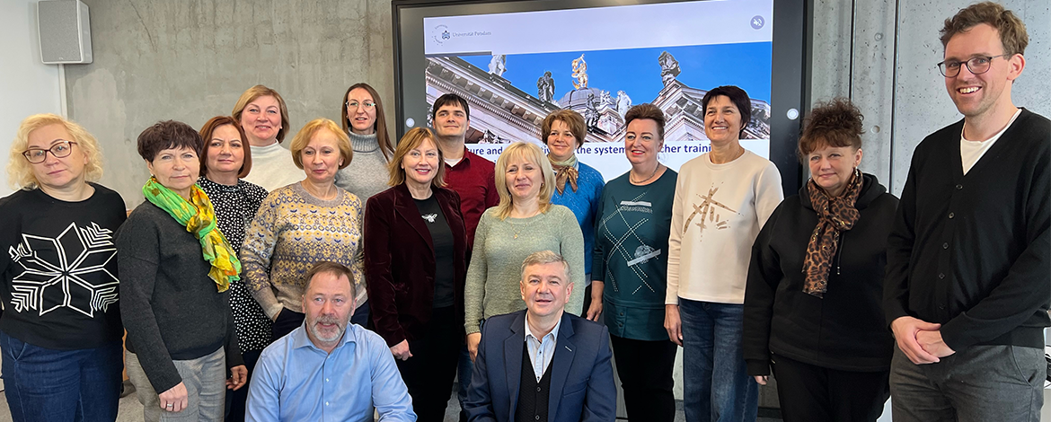 Eine Gruppe von Lehrkräften aus Litauen zu Besuch. Gruppenfoto vor einem Präsentation des ZeLB im Hintergrund.